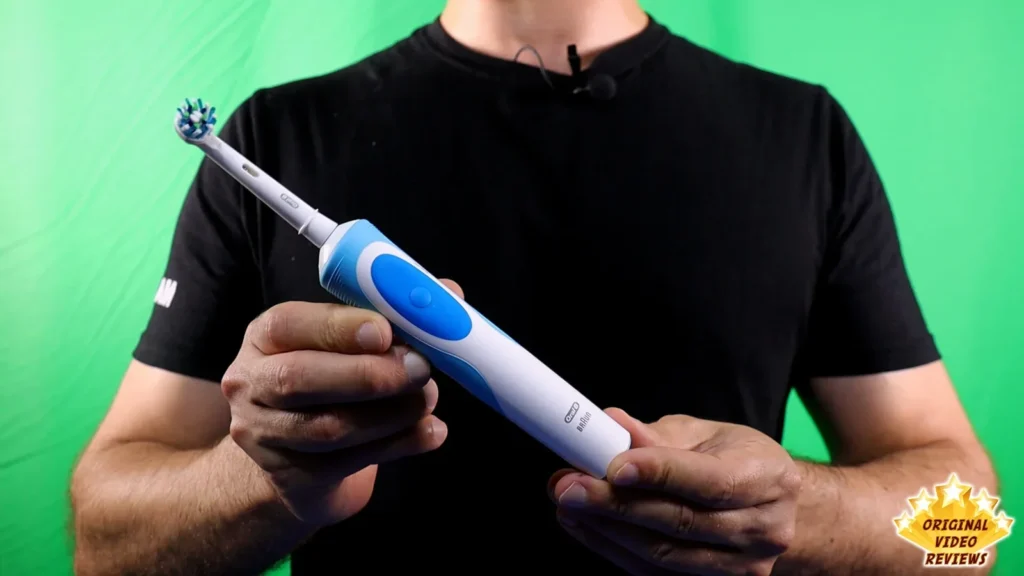 Person in a black shirt holding the Oral-B Vitality electric toothbrush in both hands, green background