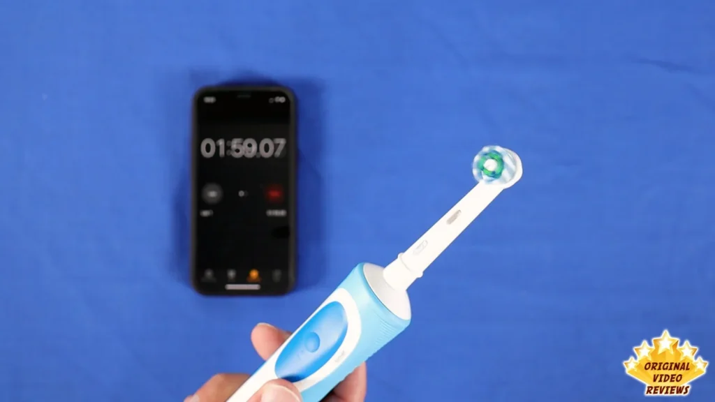 Oral-B Vitality electric toothbrush next to a phone showing a stopwatch, blue background