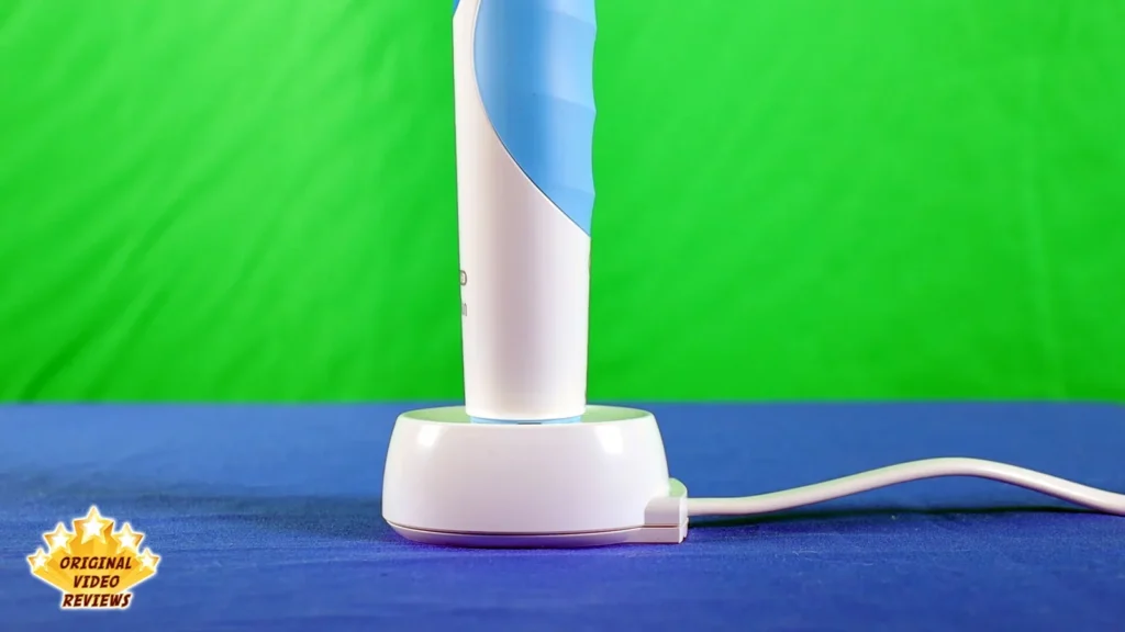 Oral-B Vitality electric toothbrush standing upright on its charging unit with the cable to the side